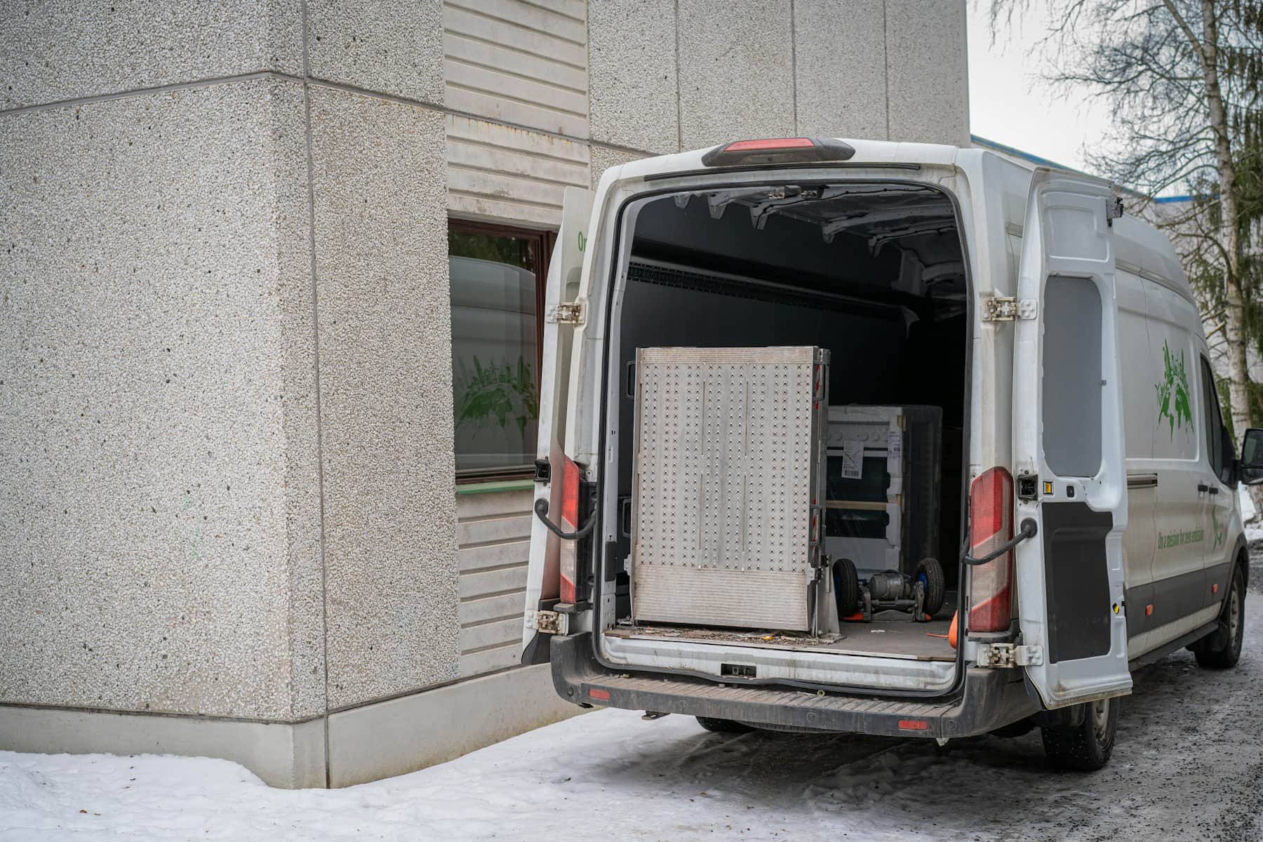 Beli kombi otvorenih zadnjih vrata, natovaren nameštajem i kutijama